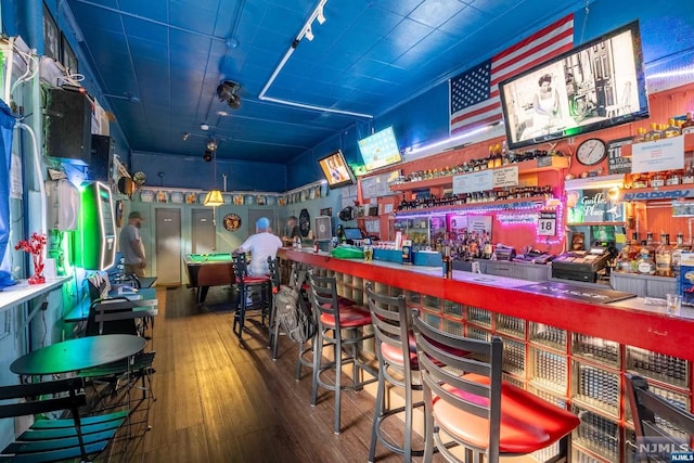 recreation room with track lighting, indoor bar, and hardwood / wood-style flooring