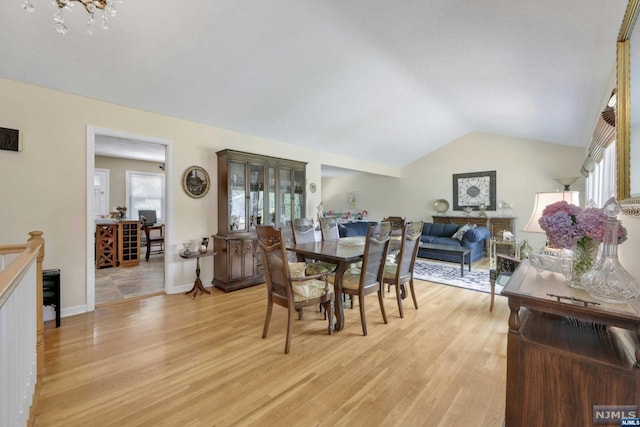 dining space featuring light hardwood / wood-style flooring, lofted ceiling, and an inviting chandelier