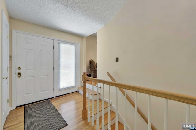 foyer entrance with a textured ceiling and light hardwood / wood-style flooring