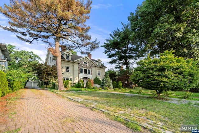 view of front of house featuring a garage, an outdoor structure, and a front yard