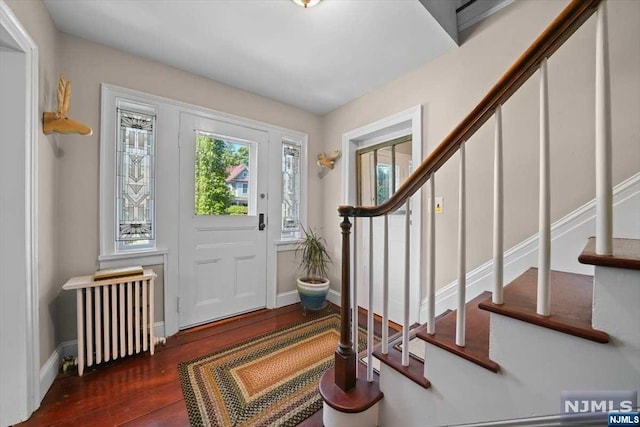 foyer entrance featuring radiator and dark wood-type flooring