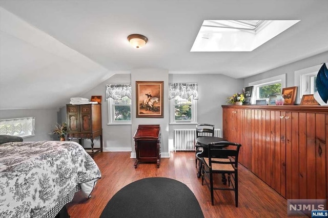 bedroom with hardwood / wood-style flooring, vaulted ceiling with skylight, and radiator