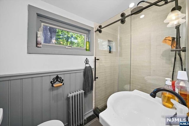 bathroom with walk in shower, radiator, and sink