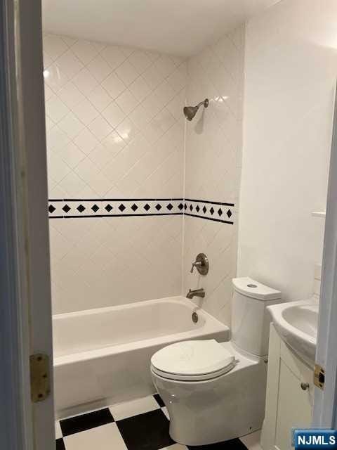 full bathroom with tiled shower / bath, vanity, and toilet