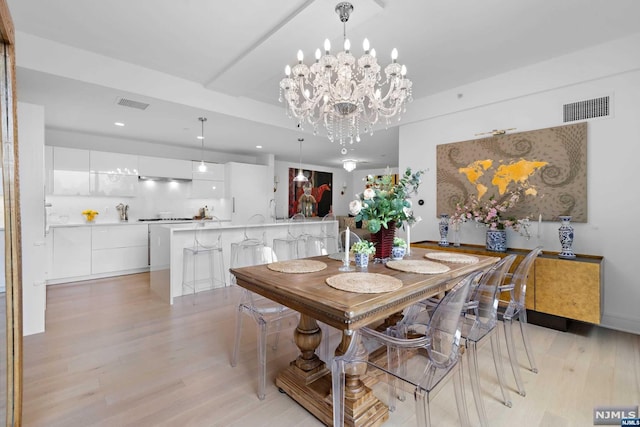 dining room with light hardwood / wood-style floors and a chandelier