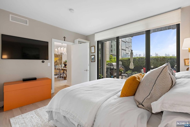 bedroom featuring light hardwood / wood-style floors, access to outside, and a chandelier