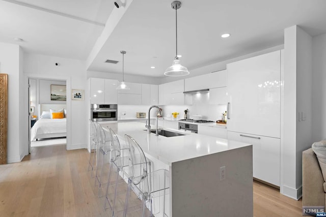 kitchen featuring white cabinets, light hardwood / wood-style flooring, oven, and sink