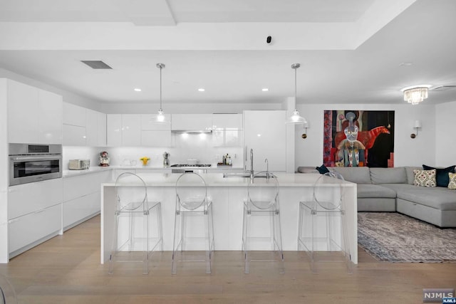 kitchen with sink, a breakfast bar area, light wood-type flooring, white cabinetry, and stainless steel appliances