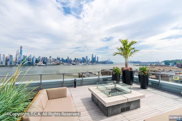 wooden deck with a water view and a fire pit