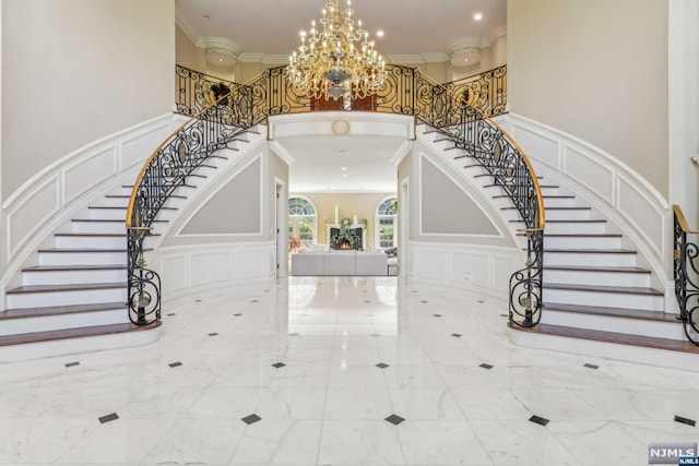 entryway featuring a notable chandelier, a towering ceiling, and crown molding