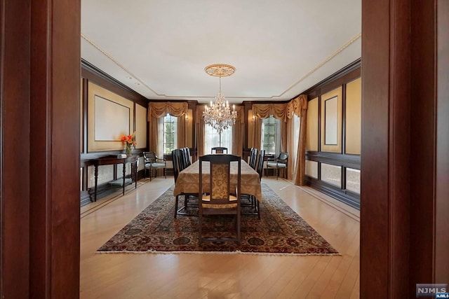 dining area with light hardwood / wood-style floors, a notable chandelier, and ornamental molding