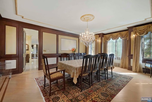 dining area with ornamental molding, light hardwood / wood-style floors, and a notable chandelier