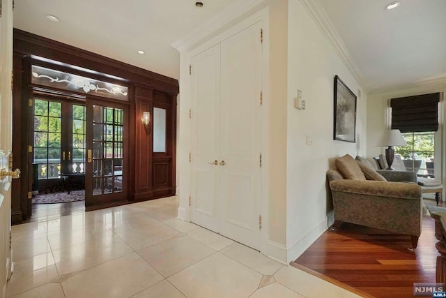 entrance foyer featuring plenty of natural light, french doors, crown molding, and light hardwood / wood-style flooring