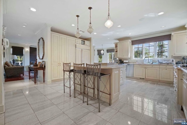 kitchen featuring dishwasher, a center island, cream cabinets, hanging light fixtures, and a kitchen bar