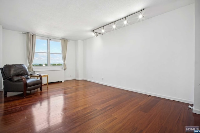 living area featuring track lighting, dark wood-type flooring, and a textured ceiling