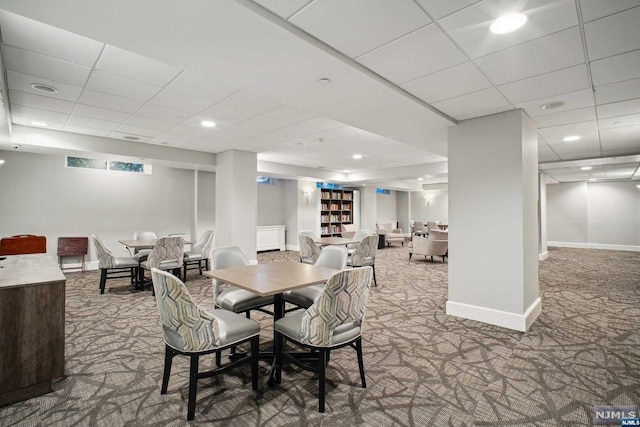 carpeted dining space with a paneled ceiling