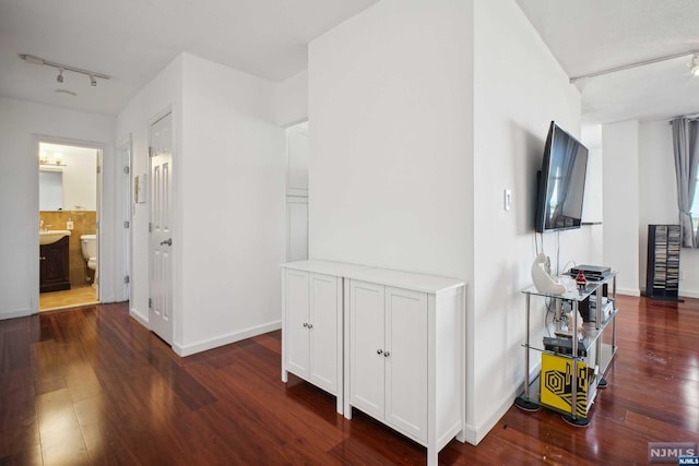 hallway featuring dark hardwood / wood-style flooring and rail lighting