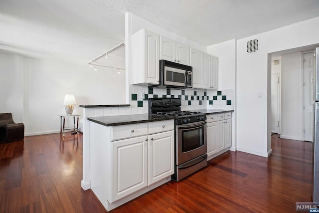 kitchen featuring white cabinetry, dark wood-type flooring, stainless steel appliances, kitchen peninsula, and decorative backsplash