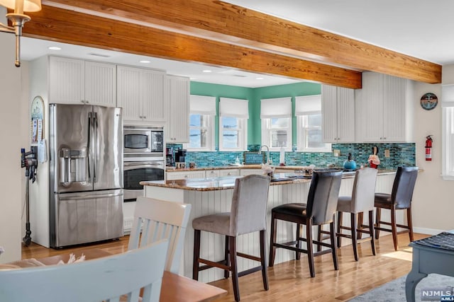 kitchen featuring stainless steel appliances, white cabinetry, light hardwood / wood-style floors, and dark stone countertops