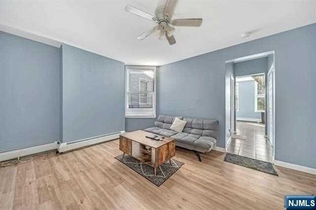 unfurnished living room featuring light wood-type flooring, baseboard heating, and ceiling fan