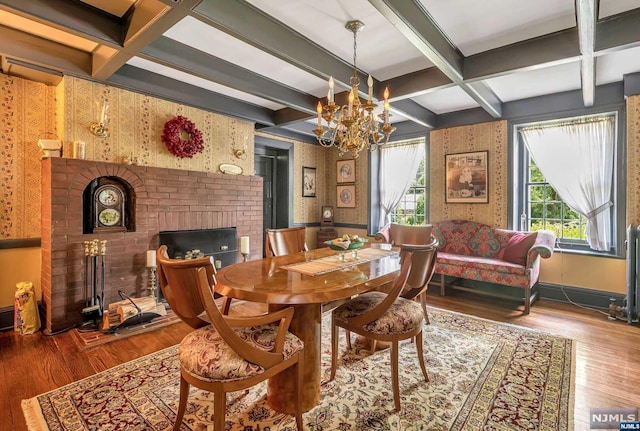 dining room with hardwood / wood-style flooring, a notable chandelier, a brick fireplace, and coffered ceiling