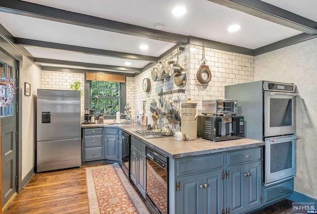 kitchen with blue cabinetry, sink, stainless steel appliances, beamed ceiling, and light hardwood / wood-style floors