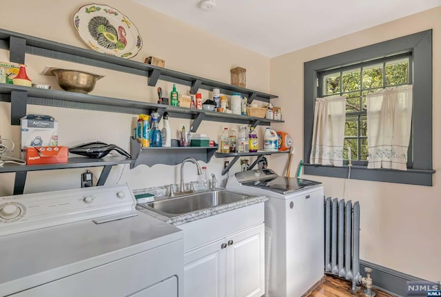 clothes washing area with radiator, sink, cabinets, light hardwood / wood-style flooring, and washer and dryer