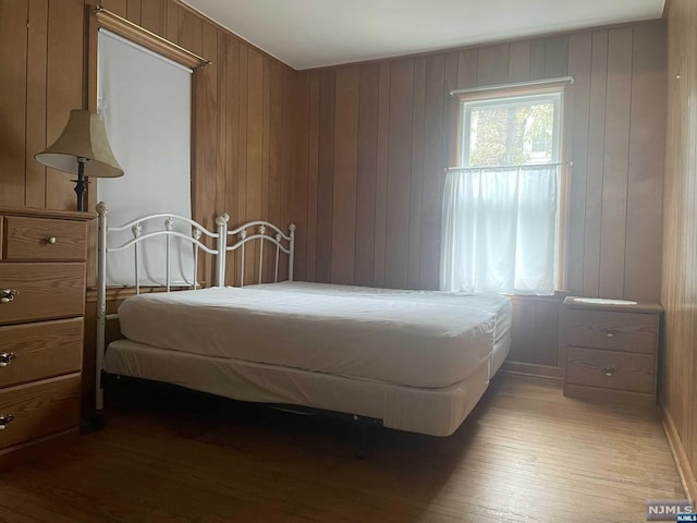 bedroom with wood-type flooring and wooden walls