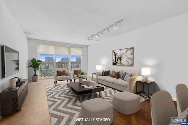 living room featuring light parquet floors, a textured ceiling, and track lighting