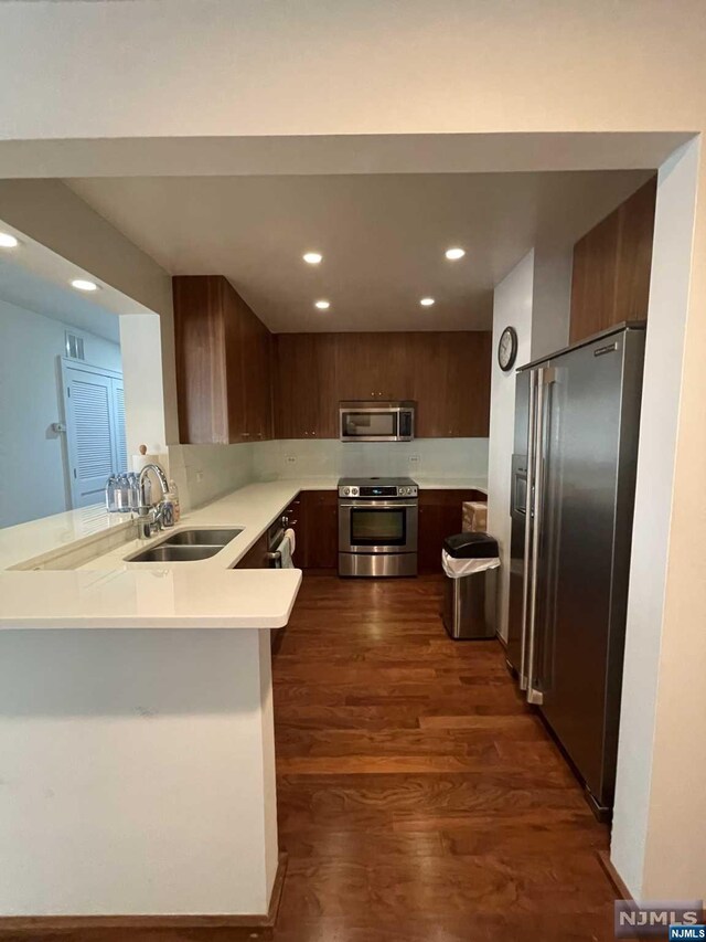 kitchen featuring dark hardwood / wood-style floors, sink, kitchen peninsula, and stainless steel appliances