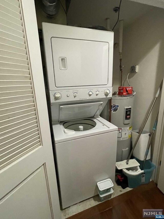 washroom featuring stacked washer / dryer and water heater