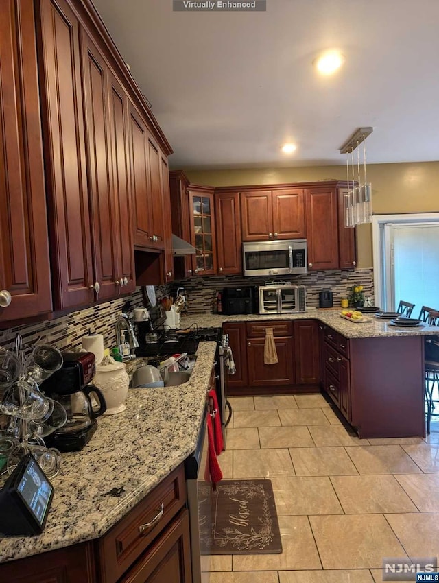 kitchen with backsplash, sink, hanging light fixtures, light tile patterned floors, and light stone counters