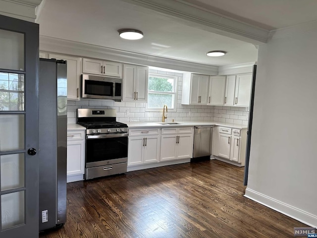 kitchen with appliances with stainless steel finishes, crown molding, sink, white cabinets, and dark hardwood / wood-style floors