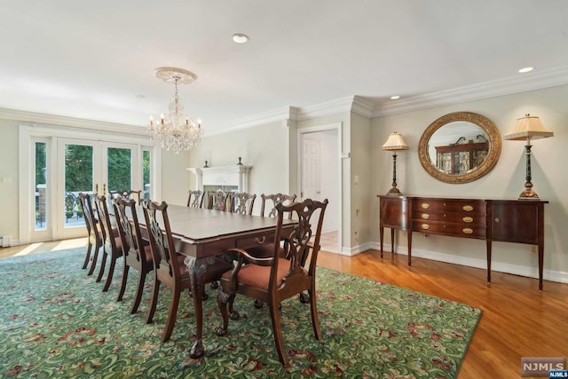 dining area featuring hardwood / wood-style flooring, a notable chandelier, ornamental molding, and french doors