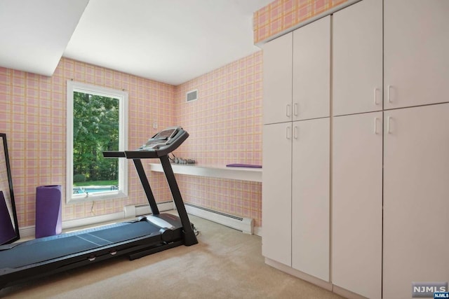 exercise area featuring light carpet and baseboard heating