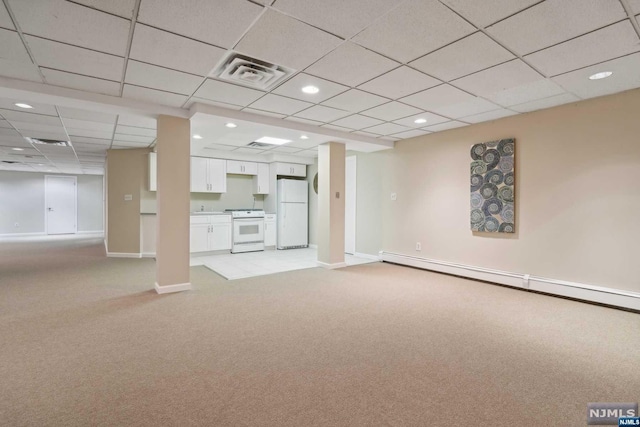 basement featuring a paneled ceiling, light carpet, white fridge, and a baseboard radiator