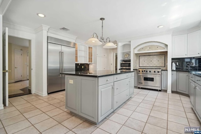 kitchen with backsplash, high quality appliances, light tile patterned floors, and decorative light fixtures