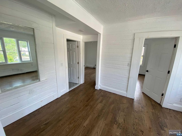 spare room with dark hardwood / wood-style flooring, a textured ceiling, and a baseboard heating unit