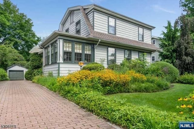 view of property exterior with a sunroom, a garage, an outdoor structure, and a yard