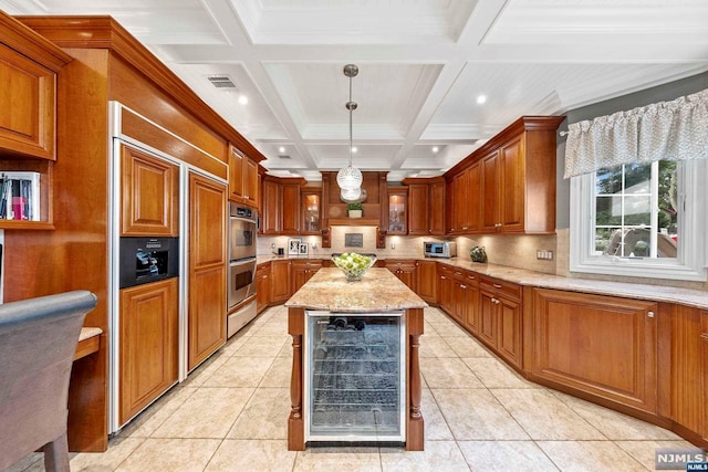 kitchen with coffered ceiling, beverage cooler, decorative light fixtures, beamed ceiling, and a kitchen island