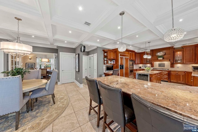 kitchen with a center island, an inviting chandelier, hanging light fixtures, and coffered ceiling