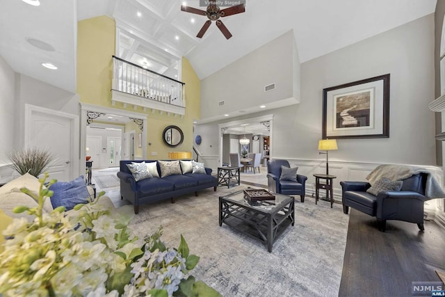 living room with beam ceiling, ceiling fan, coffered ceiling, hardwood / wood-style floors, and a towering ceiling