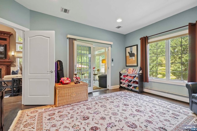 recreation room featuring a fireplace, dark wood-type flooring, and a baseboard heating unit