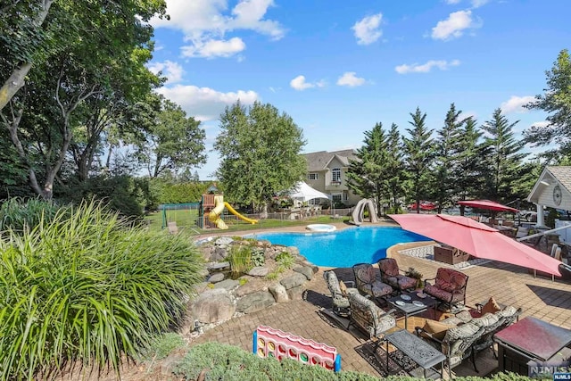 view of swimming pool with a patio and a playground