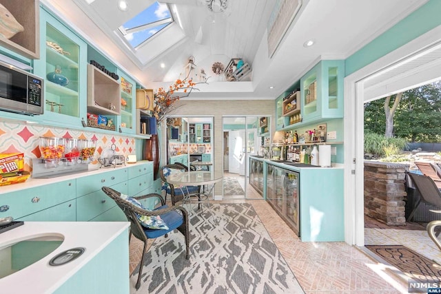 kitchen with lofted ceiling with skylight, crown molding, and tasteful backsplash