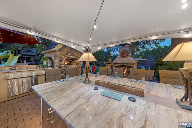 view of patio / terrace with an outdoor stone fireplace and exterior kitchen