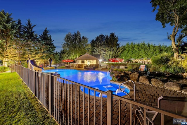 pool at dusk with a patio and a water slide