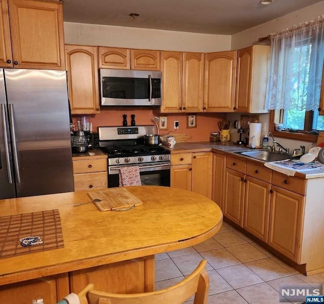 kitchen featuring sink, light tile patterned flooring, and appliances with stainless steel finishes