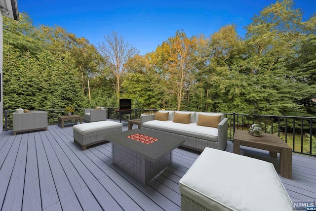 deck featuring an outdoor living space with a fire pit