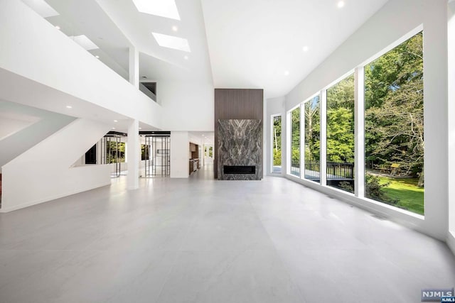 unfurnished living room with a premium fireplace and a towering ceiling